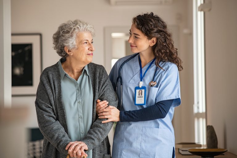 Young Caregiver Helping Senior Woman Walking.